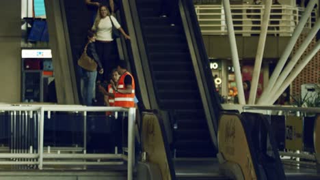 Trabajadores-Del-Aeropuerto-Y-Viajeros-Que-Viajan-En-Escaleras-Mecánicas-Dentro-Del-Aeropuerto,-En-Cámara-Súper-Lenta