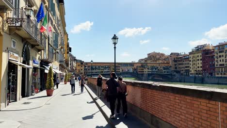 Parejas-En-Un-Romántico-Paseo-Por-El-Paseo-Del-Río-Amo-En-Un-Día-Soleado,-Florencia,-Italia.