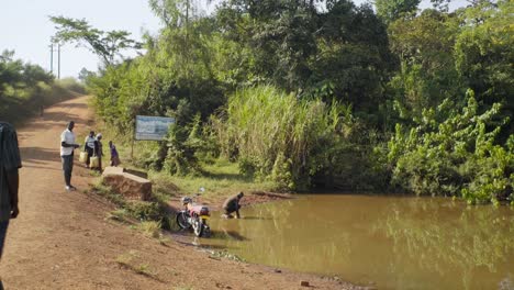 Villagers-standing-around-a-contaminated-puddle-while-a-boy-is-fetching-water-in-rural-Uganda