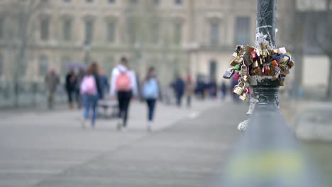 Clip-Mit-Liebesschlössern-An-Einer-Stange-Im-Stadtzentrum-Von-Paris,-Mit-Menschen,-Die-Im-Hintergrund-Laufen