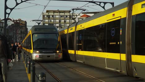 Panning-Slow-Motion-Shot,-Metro-Tram-Train-Passing-by-Each-Other-at-Don-Luis-I-Bridge-in-Porto,-Portugal,-People-walking-around-in-the-background