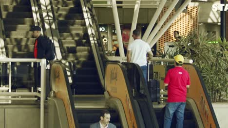 Reisende-Mit-Gepäck-Fahren-Auf-Rolltreppen-In-Einem-Flughafen,-Superzeitlupe