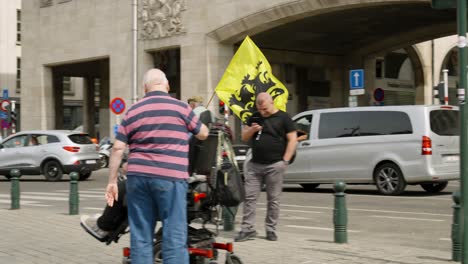 Senior-supporter-of-Flemish-far-right-party-Vlaams-Belang-waving-with-Flag-of-Flanders-on-bike-during-protest-rally-in-the-city-center-of-Brussels,-Belgium