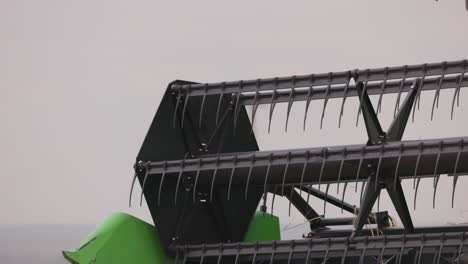 Close-up-shot-of-harvest-combine-harvesting-wheat-from-a-ripe-wheat-field-on-a-cloudy-day