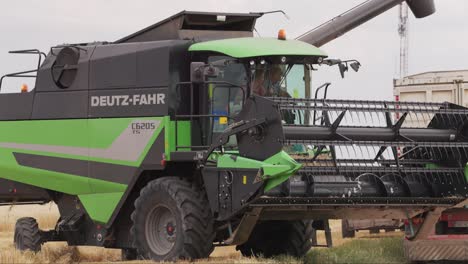 Shot-of-harvester-combine-pouring-wheat-grains-into-truck-on-field