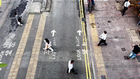 Toma-De-Arriba-Hacia-Abajo-De-Personas-De-Hong-Kong-Con-Máscaras-Faciales-Cruzando-Una-Pequeña-Carretera