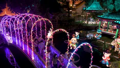 Wide-shot-view-of-Chinese-visitors-walking-through-a-bridge-decorated-with-lights-as-they-enjoy-a-nighttime-lantern-show-at-the-Wong-Tai-Sin-temple-during-the-Mid-Autumn-Festival