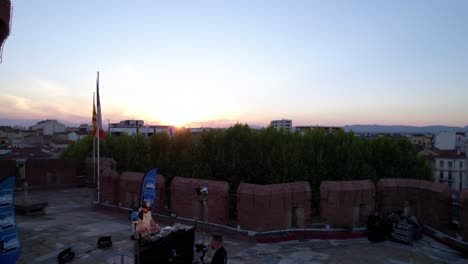 Aerial-view-during-sunset-of-a-DJ-on-top-of-Le-Castillet,-in-Perpignan,-France