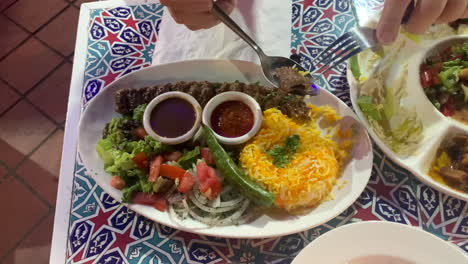 A-mediterranean-turkish-dish-on-a-plate-with-man-hands-holding-cutleries