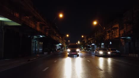 Rückansicht-Pov,-Der-Fahrzeugverkehr-Fährt-Nachts-Auf-Der-Dunklen,-Nassen-Bangkoker-Straße