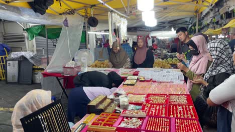 Variedad-De-Joyas-Expuestas-Cuidadosamente-Y-Una-Multitud-De-Personas-Que-Tienen-Buenas-Gangas-Con-El-Joyero-En-El-Pasar-Malam-Local-En-Jalan-Tuanku-Abdul-Rahman,-Kuala-Lumpur,-Malasia