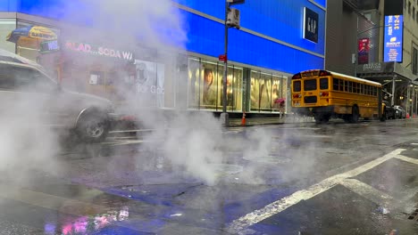 Steam-Coming-Out-Of-Manhole-Cover-In-The-Street-On-Rainy-Day-With-People-Walking-Past-Holding-Umbrellas