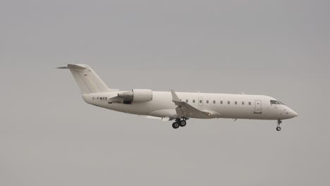 Tracking-shot-of-a-white-airplane-with-tail-number-C-FWRR-mid-fly-with-gray-clouds-in-the-background