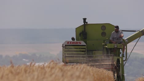 Toma-En-Cámara-Lenta-De-Una-Cosechadora-Cosechando-Trigo-En-Un-Campo-De-Trigo-Maduro-En-Un-Caluroso-Día-De-Verano