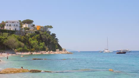 Pan-shot-of-tourists-enjoying-along-Marina-grande-shoreline-in-Capri,-Italy-on-a-sunny-day