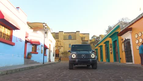 Vista-Aérea-De-ángulo-Bajo-Del-Mercedes-Benz-Clase-G-Conduciendo-Por-Calles-Coloridas-En-América-Del-Sur