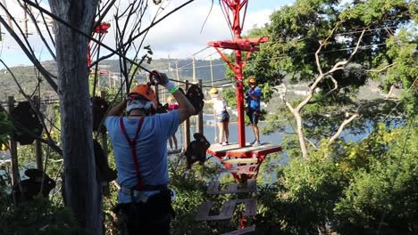 Hombre-Con-Equipo-De-Seguridad-Caminando-Por-Pasarelas-Colgantes-En-Un-Parque-De-Aventuras