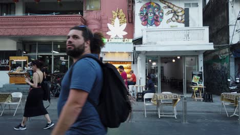 People-walk-past-Thai-Cannabis-Club-shop-on-Thanon-Khao-San-Road,-Bangkok