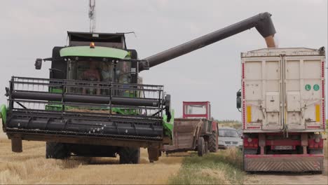 Toma-En-Cámara-Lenta-De-Una-Cosechadora-Que-Vierte-Grano-En-Un-Camión-En-El-Campo-En-Un-Día-Nublado