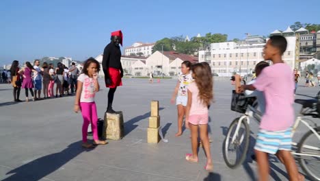 Street-performer,-saci,-performing-for-children-at-Praca-Maua,-in-the-center-of-Rio-de-Janeiro,-Brazil,-on-a-Sunday-afternoon