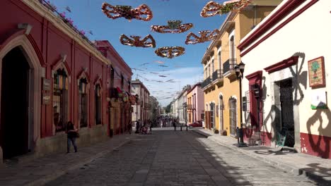 Streets-of-the-state-capital-with-hummingbird-decorations-hanging-above-while-people-walk,-Dolly-in-shot