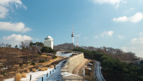 Lapso-De-Tiempo-De-Las-Nubes-Moviéndose-Sobre-La-Torre-De-Seúl-Y-La-Fortificación-De-La-Muralla-De-La-Ciudad-En-El-Parque-Namsan-De-Invierno-Acercar