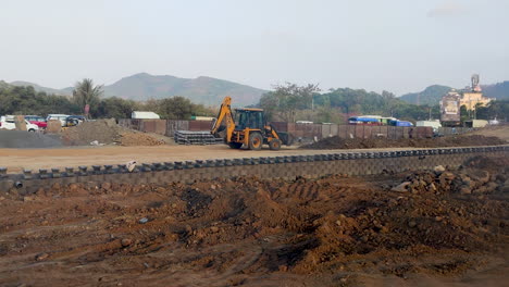 Inmitten-Der-Hektik-Des-Geschäftigen-Straßenverkehrs-In-Indien-Arbeitet-Ein-JCB-Bagger-Unermüdlich-Am-Straßenrand-Und-Trägt-Zum-Straßenbau-Bei