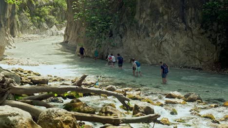 Group-of-gorge-explorers-hold-on-to-safety-rope-crossing-rapid-ravine-river