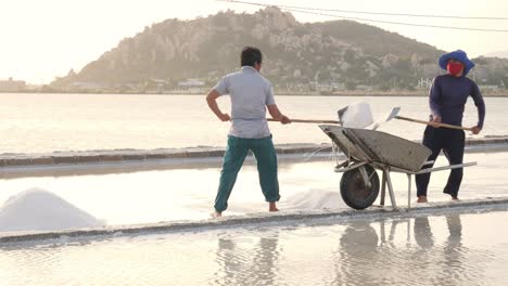 Dos-Agricultores-De-Sal-Marina-Están-Recolectando-Sal-Marina