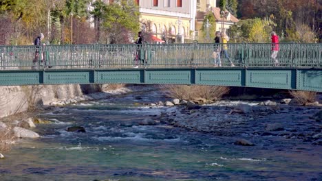 Los-Peatones-Cruzan-Un-Puente-Peatonal-Sobre-El-Río-Passer-En-Meran---Merano,-Tirol-Del-Sur,-Italia