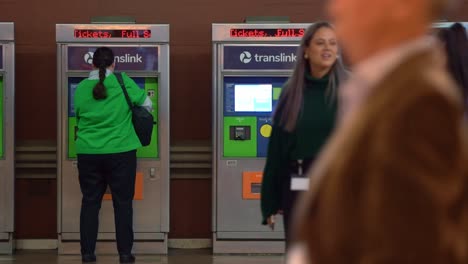 Horas-Pico-Fuera-Del-Trabajo-En-La-Estación-Central-De-La-Ciudad-De-Brisbane,-Los-Viajeros-Corren-Hacia-El-Andén-Y-El-Viajero-Compra-El-Billete-En-La-Máquina-Expendedora-De-Autoservicio-En-El-Fondo,-Toma-Estática