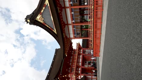 Touristen,-Die-Um-Fukakusa-Yabunouchicho-Herumlaufen,-Mit-Turmtor-Im-Hintergrund-Am-Fushimi-Inari-Schrein