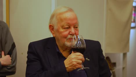 Un-Hombre-Blanco-Mayor-Y-Bien-Vestido-Con-Barba-Bebiendo-De-Un-Vaso-Lleno-De-Vino-Tinto