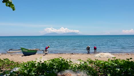 Local-Timorese-fishermen-searching-and-looking-for-fishing-bait-along-the-sandy-beach-coastline-of-Dili,-Timor-Leste