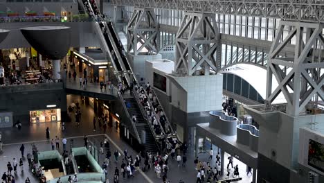 Blick-Hinunter-Auf-Das-Belebte-Atrium-Des-Bahnhofs-Kyoto-Mit-Menschen,-Die-Auf-Der-Rolltreppe-Auf-Und-Ab-Gehen,-Japan