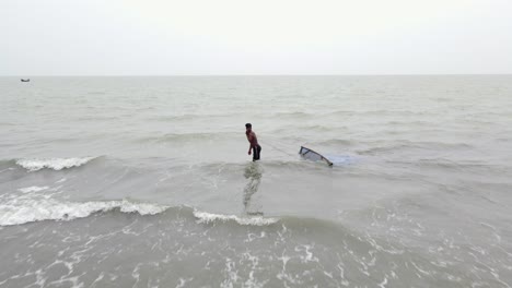 Pescador-Arrastrando-Red-De-Pesca-A-Través-De-Las-Olas-Del-Mar-En-La-Playa-De-Kuakata,-Bangladesh