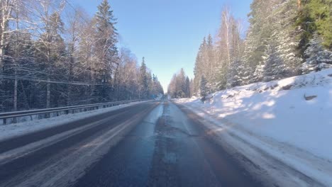 Mientras-El-Coche-Avanza-Por-La-Carretera,-A-Su-Lado-Hay-Pinos-Cubiertos-De-Nieve,-Creando-Una-Pintoresca-Escena-Invernal.