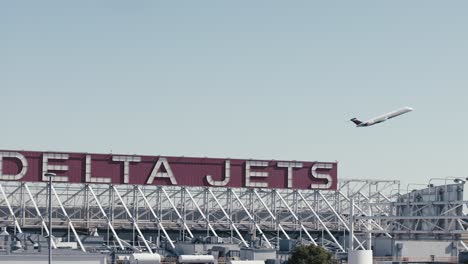 Un-Avión-Comercial-De-Delta-Despega-Mientras-Las-Aerolíneas-Delta-Firman-En-El-Aeropuerto-Atl-De-Atlanta,-Georgia,-Enmarca-La-Escena.