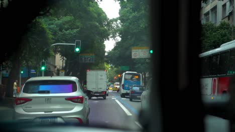 Car-traffic-in-Rio-de-Janeiro-with-streets-full-of-vegetation-Brazil-green-traffic-light,-hidden-perspective