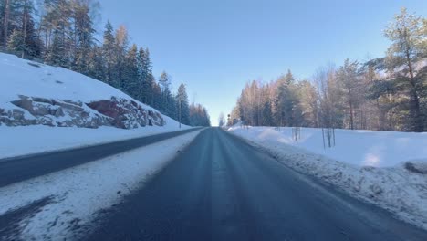 As-the-car-travels-along-the-road,-snow-laden-trees-line-its-sides,-painting-a-scenic-winter-landscape-that-adds-a-touch-of-natural-beauty-to-the-journey