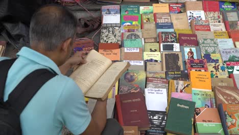 Un-Hombre-Está-Leyendo-Ansiosamente-Un-Viejo-Libro-Vendido-En-La-Calle