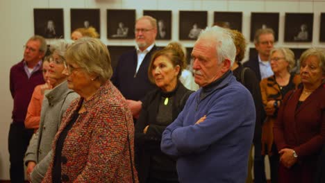 Group-of-well-dressed-older-males-and-females-carefully-listening-at-reception