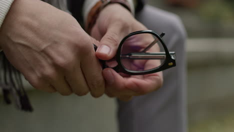 Close-up-on-man’s-hands-nervously-holding-glasses-outdoors-in-the-park-alone