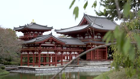 Hintergrundfokusaufnahme,-Vorbei-An-Blättern-Und-Ästen,-Blick-Auf-Die-Phönixhalle-Im-Buddhistischen-Byodo-in-Tempel-In-Uji