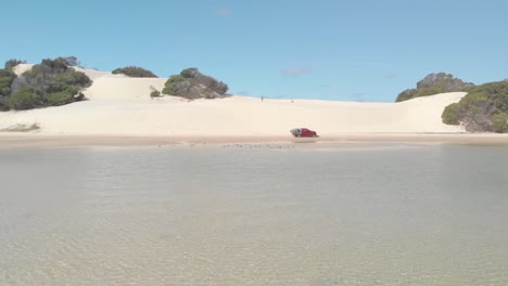 Disparo-Aéreo-De-Un-Dron-Sobrevolando-Un-Coche-Y-Un-Hombre-En-Una-Playa-Australiana-Llena-De-Dunas-De-Arena,-En-Queensland,-Australia