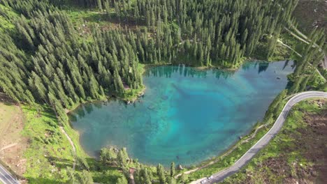 Reflexión-En-El-Lago-Carezza-Tomada-Con-Un-Dron-En-Los-Alpes-Italianos,-Dolomitas-Mientras-Hay-Montañas-Al-Fondo