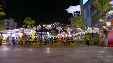 Los-Compradores-Nocturnos-Se-Detienen-En-Un-Mercado-Callejero-Cercano-Para-Comprar-Algo-De-Comida-En-Los-Puestos-De-Comida-De-La-Ciudad-De-Bangkok,-Tailandia