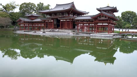 Neigen-Sie-Sich-Von-Der-Spiegelung-Von-Byodo-In-Den-Teichsee,-Der-Ihn-In-Uji-Umgibt,-Nach-Oben,-Um-Die-Phönixhalle-Freizulegen