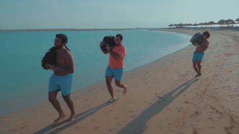 Athletes-Racing-by-The-Shore-carrying-sandbags-at-shoulders---Slow-Motion