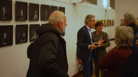 Un-Hombre-Mayor-De-Pelo-Gris-Con-Barba-Y-Una-Mujer-Comunicándose-Hablando-Y-Bromeando-En-La-Feria-De-Arte